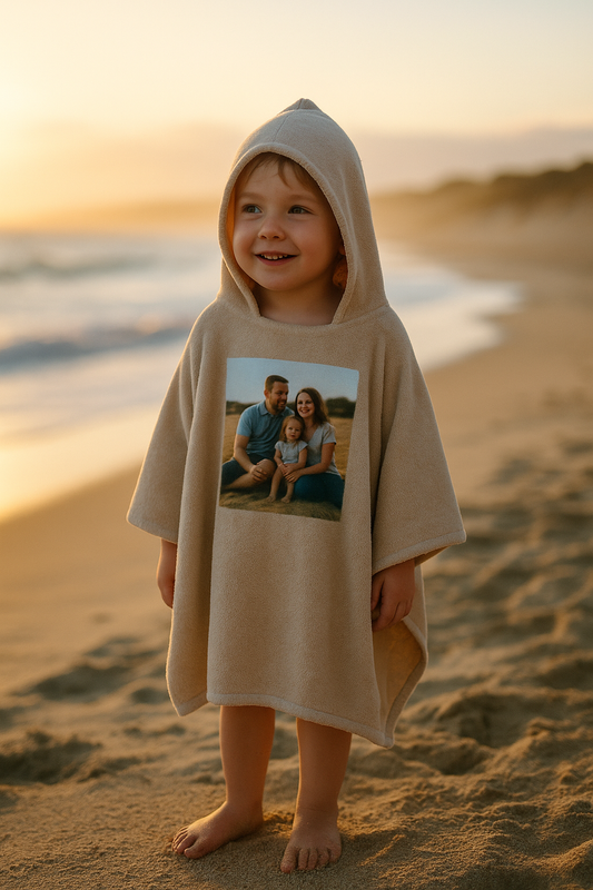 Child wrapped in custom photo kids hooded towel at golden hour beach, smiling after first swim.